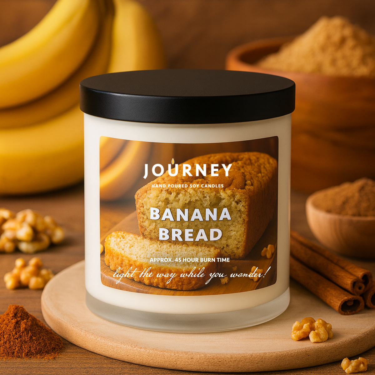 Candle labeled 'Journey' with banana bread design on a wooden surface with bananas and spices.